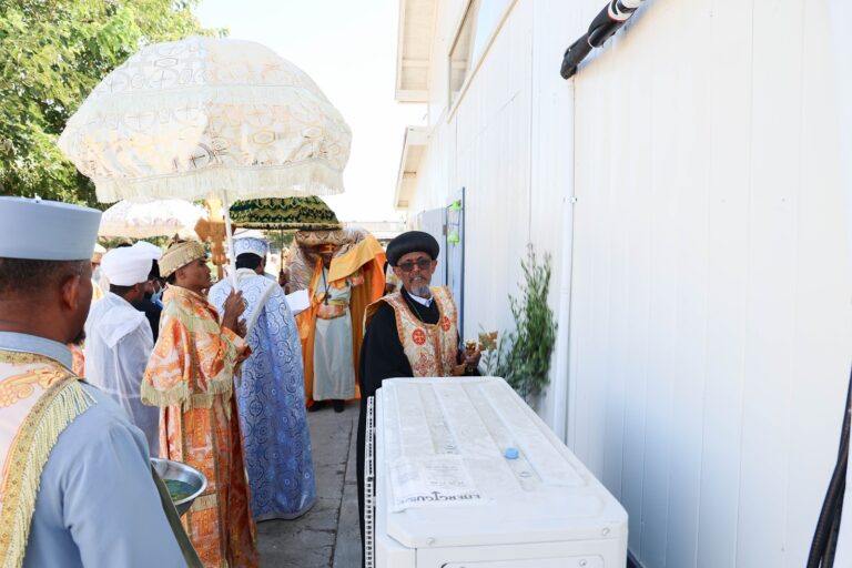 The procession with ceremonial umbrellas beside the new church